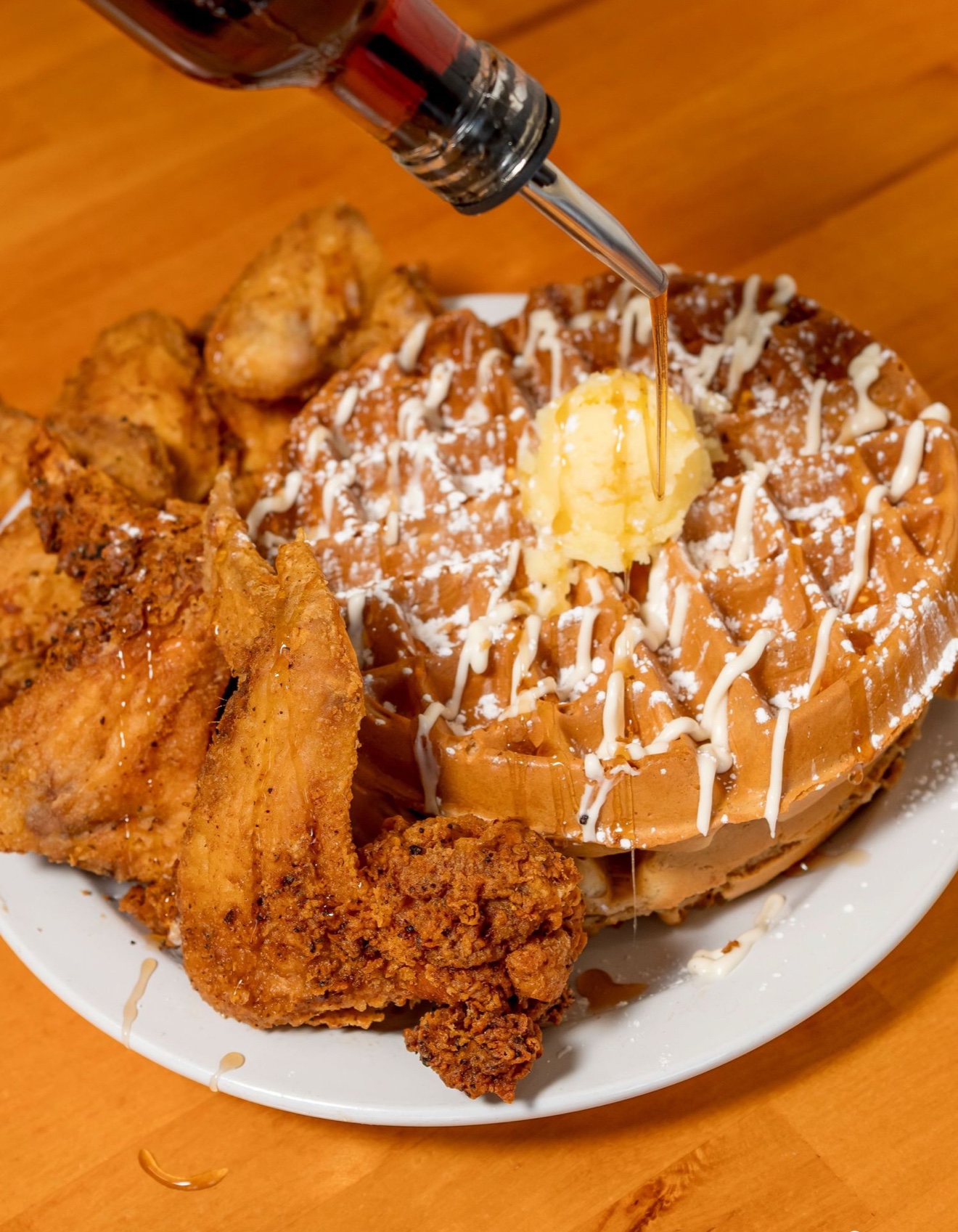 Sunrise Social chicken and waffles with syrup pouring over the plate